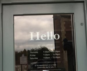 Image of a door with word Hello and opening times